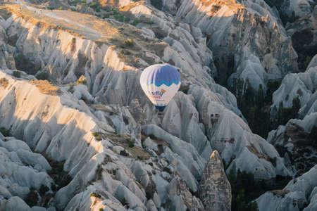 GOREME, TURKEY - AUGUST 3, 2021: One lonely colorful hot air balloon flying very close to the ground over the Cappadocia valley in the morning lightのeditorial素材