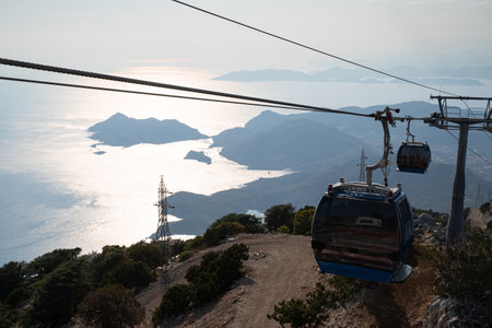 OLUDENIZ, TURKEY - JULY 25, 2021: Teleferik cable cars from Oludeniz to Babadag peak with view of...