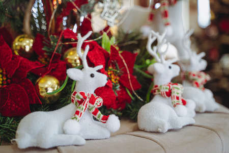 closeup front view of Christmas festive decoration with white plush textile reindeers wearing warm red scarfs and globes  near the fir treeの写真素材