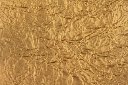 top view detail closeup of textured wrapping paper gold foil leaf with wrinkled surface and embossed...