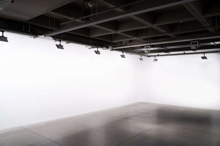 front view of exhibition industrial style interior with lights and empty white wallsの写真素材