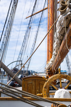 A detailed view of a wooden ship wheel surrounded by rigging elements on a historic sailing ship...