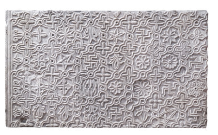 A closeup view of a carved stone tile featuring intricate floral and geometric patterns