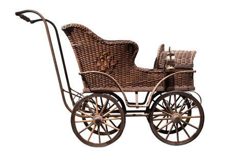 A detailed view of a vintage wicker baby carriage with metal wheels isolated on whiteの写真素材