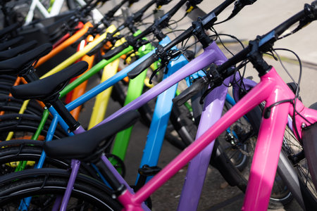 A row of brightly colored bicycles neatly parked outdoors with vibrant frames creating a cheerful urban atmosphereの写真素材