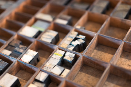 A detailed view of vintage wooden letterpress type blocks arranged in a drawer showing textures