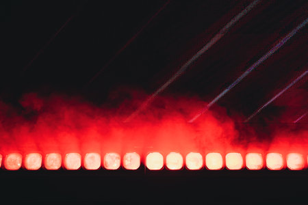A vibrant display of bright red stage lights with a smoky atmospheric effect in a dark setting