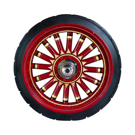 A vintage wagon wheel with red and black spokes featuring intricate decorative details and shiny hubcapの写真素材