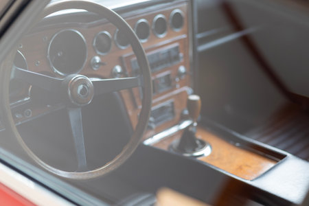 Interior of a classic vintage car showcasing wooden panel details and retro steering wheel in soft...
