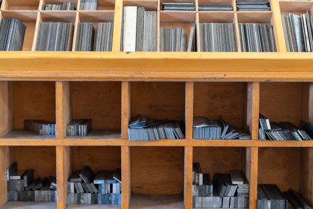 Neatly organized metal letter blocks arranged in a vintage wooden drawer for traditional printing purposesの写真素材