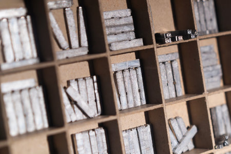 Closeup of vintage metal printing blocks arranged in a wooden drawer used for traditional letterpress printingの写真素材