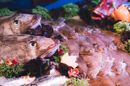 Fresh fish and seafood displayed on ice with vegetables and greens at a seafood market