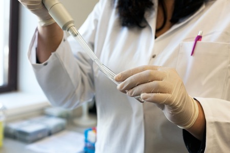 Closeup of a female scientist filling test tube with pipette in labの写真素材