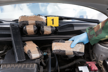 Police officer holding drug package discovered in engine compartの写真素材