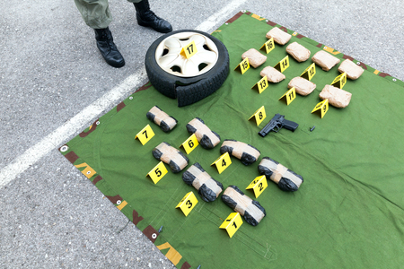 Police officer standing guard over seized packages of drugの写真素材