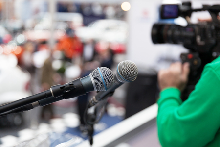 Microphone in focus against blurred cameraman holding video cameraの写真素材