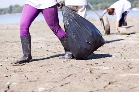Environmental activist is collecting plastic waste at river or lake coast