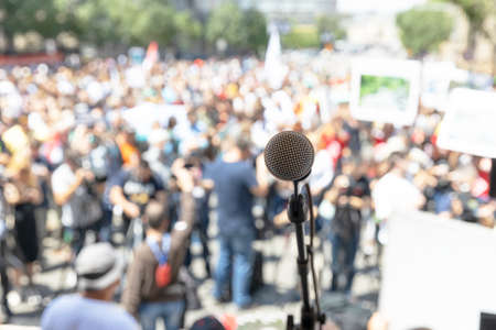 Focus on microphone, blurred group of people at protest in the background