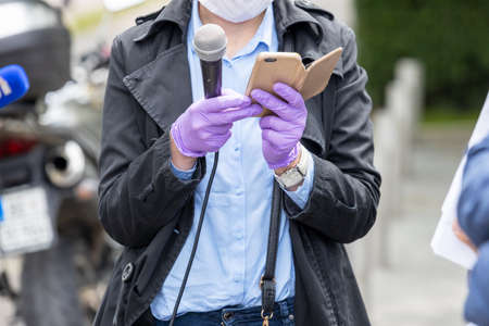 Female journalist wearing protective gloves and face mask against coronavirus COVID-19 disease...