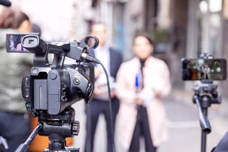 Filming media event or news conference with video camera and smartphone. Mobile journalism concept.の写真素材