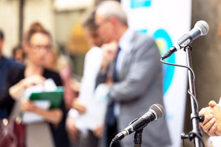 Microphone in focus at press conference or business presentation, blurred people in the backgroundの写真素材
