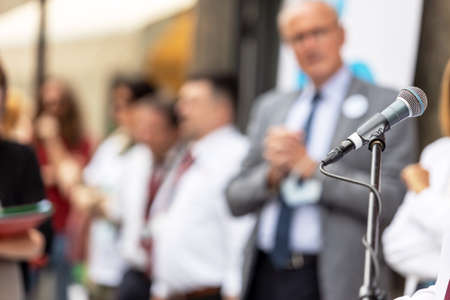 Microphone in focus at news conference or business presentation, blurred people in the backgroundの写真素材