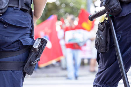 Police on duty during street protest, blurred protester in the backgroundの写真素材