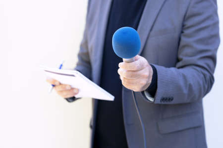 Reporter holding microphone making media interviewの写真素材