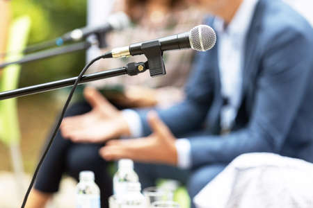 Microphone in focus against blurred people at round table event or business conference