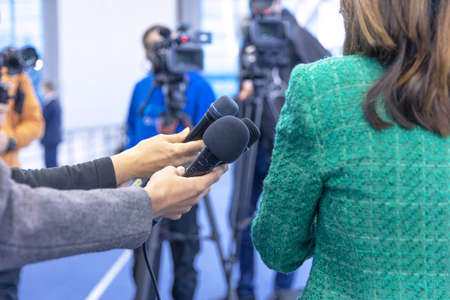 Journalists at news conference holding microphones making media interview with female politician or business womanの写真素材
