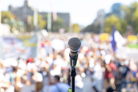 Protest or public demonstration, focus on microphone, blurred crowd of people in the background