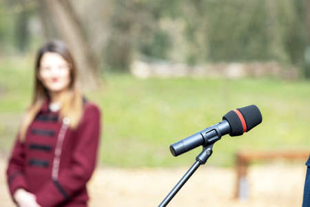 Microphone in focus, blurred female person in the backgroundの写真素材