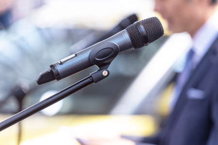 Public speaking or relations with copy space concept. Microphone in focus, blurred unrecognizable...