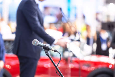 Public speaking or relations with copy space concept. Microphone in focus, blurred unrecognizable person in the background.の写真素材