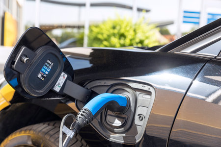 Electric vehicle with plug-in socket at charge station charging battery