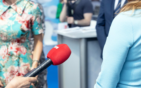 Journalist at news conference holding microphone making media interview with female politician or business womanの写真素材