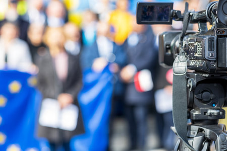 Filming political meeting or media event with television camera, European Union flag in background