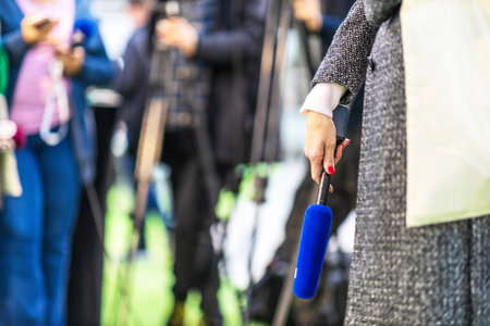 Journalist holding microphone at media event or press conferenceの写真素材