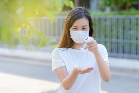 Asian people using alcohol antiseptic gel and wearing prevention mask,prevent against infection of Covid-19 outbreak,woman washing hands with hand sanitizer to avoid contaminating with Corona virusの写真素材
