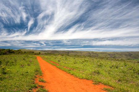 Rural orange dirt road with blue sky and far horizonの写真素材