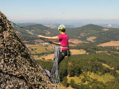 Woman rock climber in a steep rock with beautiful landscape in the background