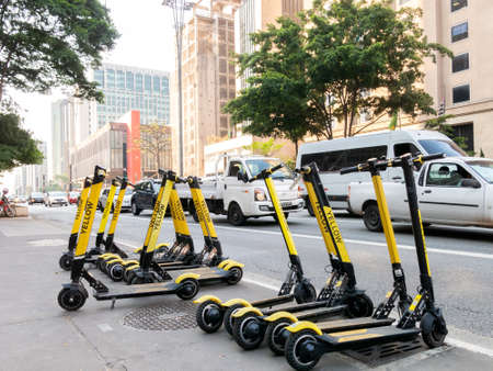 SAO PAULO, BRAZIL - OCT 25, 2019 - Yellow scooters for rent in SÃ£o Paulo Paulista sidewalk...