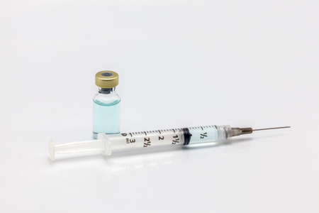 Isolated glass vaccine bottle with colored liquid and a full of colored liquid syringe