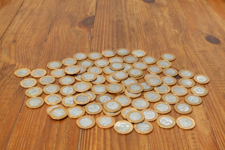 A pile with a lot of Real brazilian money coins on a wood table