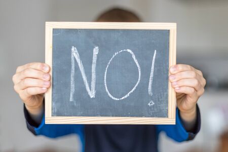 Boy holds chalkboard with NO lettersの写真素材