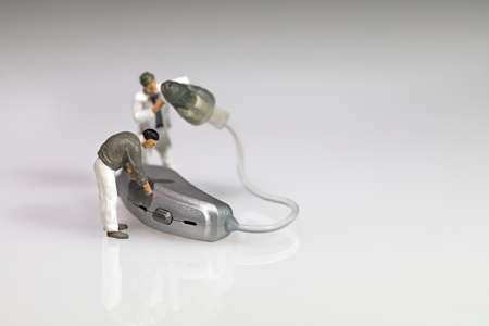 miniature figures doing hearing aid maintenance