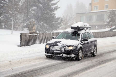 station wagon with roof box on snowy streetの写真素材