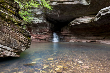 A waterfall flowing out of a cave along the lost valley trail in Arkansas.の写真素材