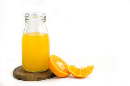 Fresh orange juice above wood coaster, with raw, sliced orange fruit â isolated on white background with studio lightingの写真素材