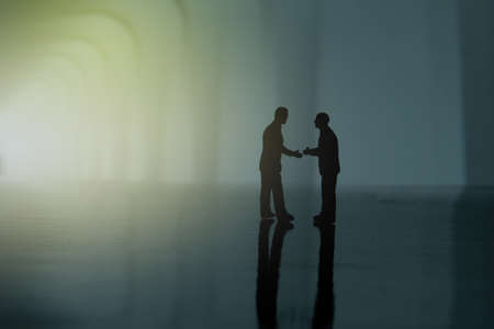 Silhouette of two businessmen make an handshake partnership agreement. Miniature people figure conceptual photographyの写真素材